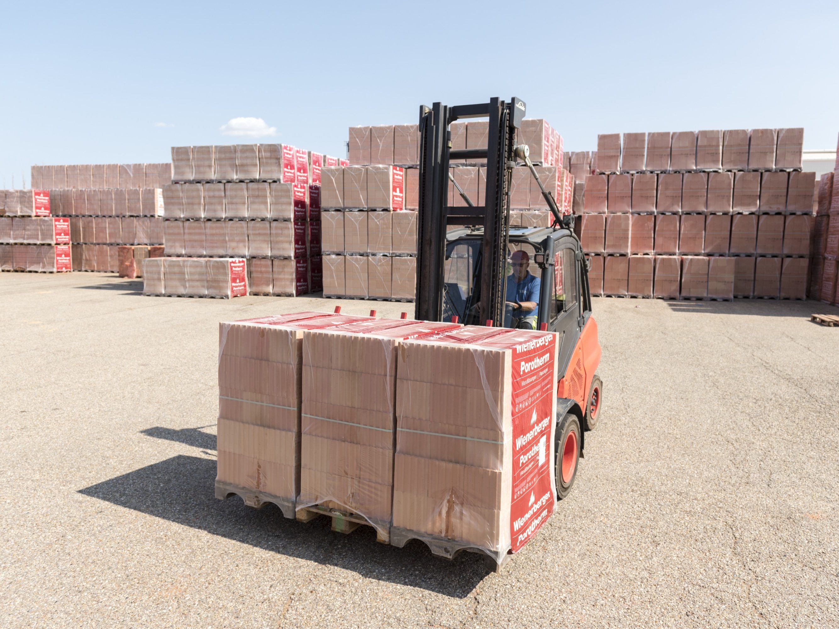 Forklift loads clay block pallets on tuck on stockyard