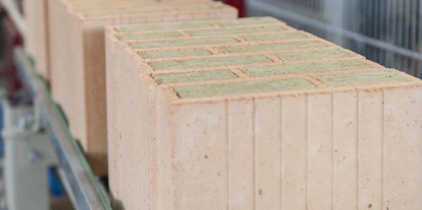 Insulation filled clay blocks on conveyor belt leaving filling station at production plant Haiding