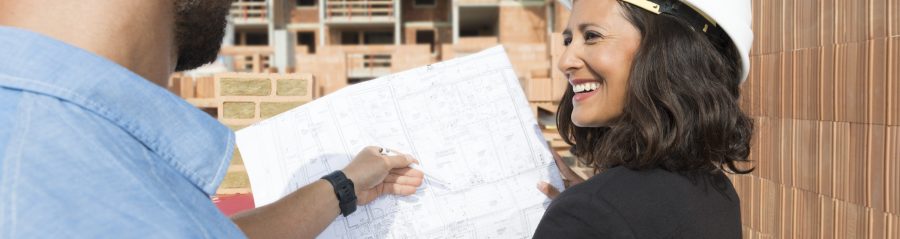 Male and female Architect with technical drawing on construction site